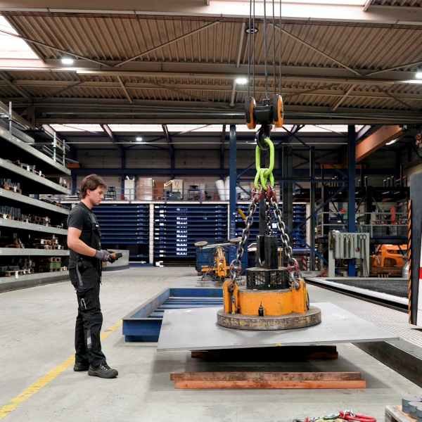 Steel plate lifted with a lifting magnet attached to an overhead crane