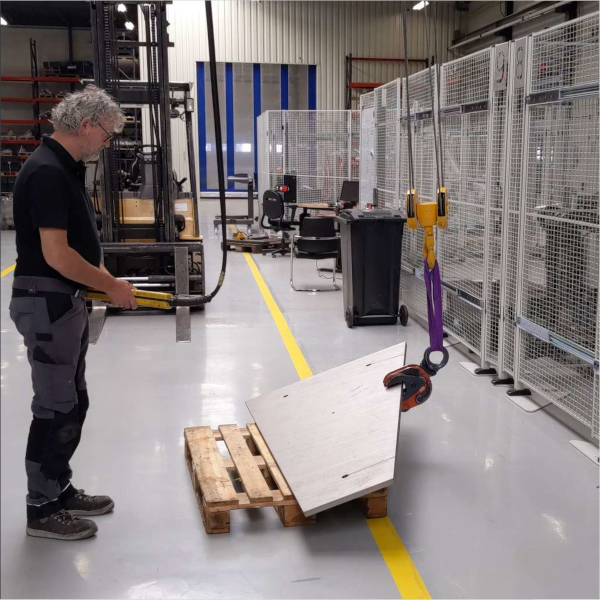 Operator turning a steel plate using a crane and lifting clamp